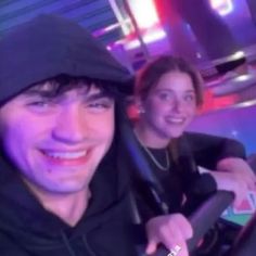 a man and woman are smiling while riding on a roller coaster at an amusement park