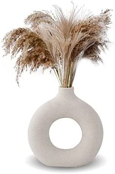 a white vase with dried grass in it