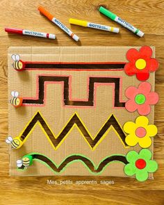 a paper bag with flowers and bees on it, next to crayon markers