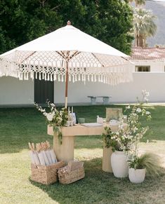 an umbrella is set up in the grass with flowers and other items on it,