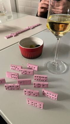 a glass of wine and some pink dominos on a table