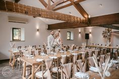 a bride and groom standing in the middle of a room with tables set for dinner