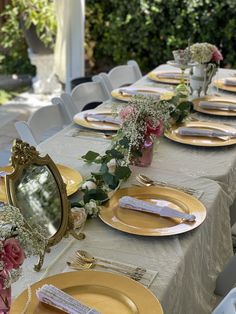 the table is set with gold plates and place settings