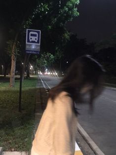 a blurry photo of a woman walking down the street at night with a bus sign in the background