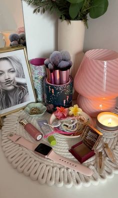 a table topped with lots of makeup and other items next to a vase filled with flowers