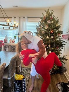 a man and woman dressed up in costumes standing next to a christmas tree with presents on the floor