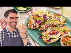 a man sitting at a table with food in front of him and the plate is full of tacos