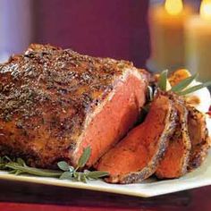 a piece of meat on a plate with candles in the background