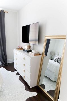 a bedroom with a large mirror, dresser and television on the wall in front of it