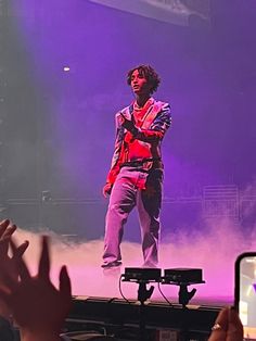 a man standing on top of a stage with his hands up in front of him