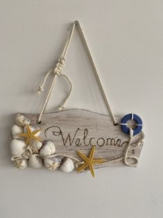 a welcome sign hanging from the side of a wall with seashells and starfish