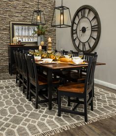 a dinning room table with chairs and a large clock on the wall behind it