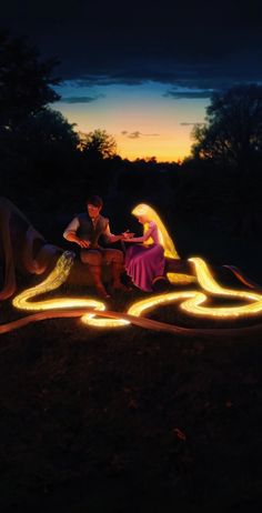 a man and woman sitting on top of a bench surrounded by fire lights at night