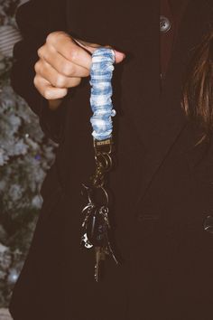 a person wearing a black coat holding a blue bottle keychain in front of a christmas tree