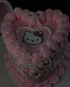 a hello kitty heart cake with pearls on the sides and pink icing in the shape of a heart