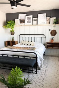 a bedroom with a bed, plants and pictures on the wall