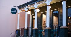 an outside view of a restaurant with columns and lights hanging from the front porchs