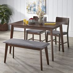 a dining room table with two benches and a potted plant in the corner next to it