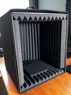 an empty speaker box sitting on top of a wooden table next to a computer keyboard