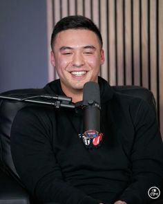 a man sitting in front of a microphone with his eyes closed, smiling at the camera