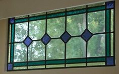 a close up of a stained glass window with trees in the backgroung