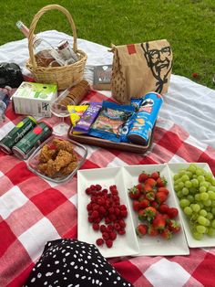 the picnic table is full of fresh fruit and snacks, including grapes, strawberries, crackers