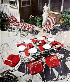 a woman standing next to a table with red and white chairs