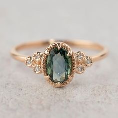 a ring with an oval green stone surrounded by small white and brown diamonds on top