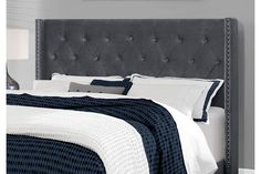 an upholstered headboard on a bed in a room with gray walls and white pillows