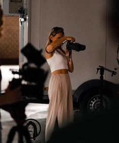 a woman in a white top is holding a camera and taking pictures with other people