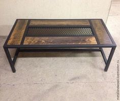 a coffee table made out of wood and metal with a grill on the top, in front of a white wall