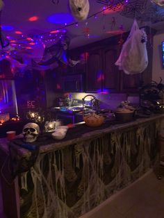 a kitchen decorated for halloween with skulls and decorations on the counter, hanging from overhead lights