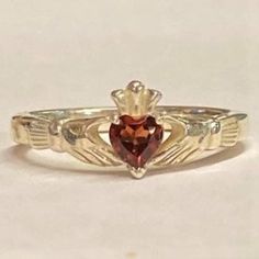 This lovely Celtic Claddagh Ring is set with a beautiful, genuine Garnet Heart. It has the Celtic symbolism of hands holding the gemstone heart which has a sterling crown. We can make this ring with any gemstone, please contact us for pricing on any stone/color. The band can be made in sterling silver or in 10k, 14k, 18k gold or in platinum. Just choose your metal from the drop-down list. While the sterling silver or platinum only come in the standard silver color, if you choose gold you can cho Classic Sterling Silver Heart Ring With Birthstone, Classic Sterling Silver Heart Ring With Gemstone, Formal Sterling Silver Heart Ring With Birthstone, Formal Heart Ring With Birthstone In Sterling Silver, Brave Wedding, Celtic Symbolism, Celtic Claddagh Ring, Gold Claddagh Ring, Puzzle Ring