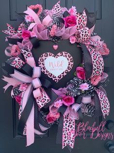 a leopard print wreath with pink and black bows on the front door for valentine's day