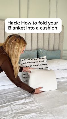 a woman laying on top of a bed with pillows in front of her and the caption that reads hack how to fold your blanket into a cushion