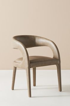 a chair that is sitting in the middle of a white floor with a beige wall behind it