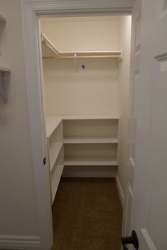 an empty walk in closet with white shelves