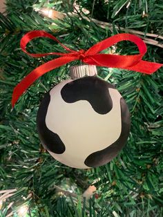 a black and white ornament hanging from a christmas tree with red ribbon on it