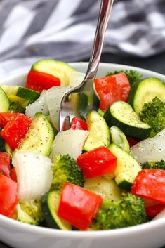 a white bowl filled with vegetables and a fork sticking out of the top of it