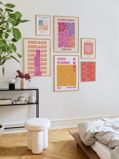 a bedroom with posters on the wall and a bed in the foreground, next to a plant