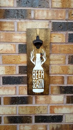 a beer sign mounted to the side of a brick wall that says beer season on it