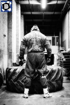 a man standing next to a large tire in a warehouse