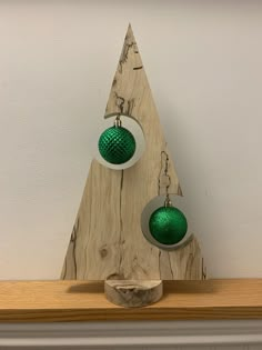 two green and white ornaments on top of a wooden shelf in front of a wall