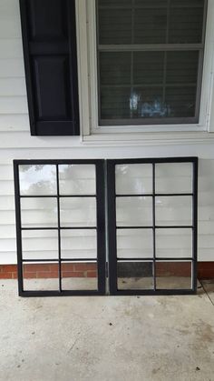 an open window on the side of a house with black shutters and glass panes