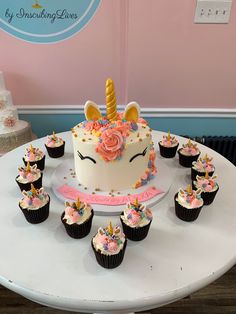 cupcakes and a cake on a table in front of a unicorn themed cake