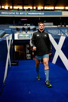 a man is standing in the middle of a blue carpeted area at a sporting event