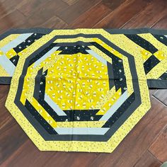 two pieces of yellow and black quilted material sitting on top of a wooden floor