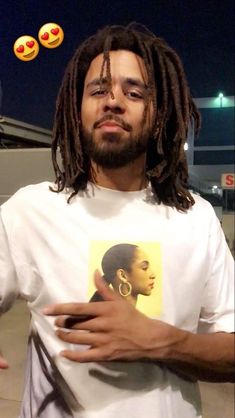 a man with dreadlocks standing in front of an emoticive image on his t - shirt