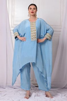 Ice blue crepe kaftan with badla, pearls and cutdana embroidered placket and cuffs. Comes with shantoon pant and an inner.
Components: 3
Pattern: Embroidered
Type Of Work: Badla, Pearls, Cutdana
Neckline: Round
Sleeve Type: Kaftan : Flared Sleeves, Inner : Sleeveless
Fabric: Shantoon, Kaftan : Crepe, Lining : Shantoon
Color: Blue
Other Details: 
Attached lining
Length :
Kaftan : 34 inches (Front) and 50 inches (Side)
Pant : 38 inches
Product Weight : 1 Kg
Occasion: Sangeet - Aza Fashions Kaftan Kurti, Embroidered Kaftan, Trendy Outfits Indian, Kaftan Top, Side Pants, Pakistani Dress Design, Butterfly Sleeves, Pant Set, Designer Suits