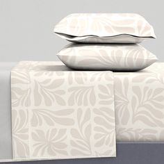 three pillows stacked on top of each other next to two sheets and pillowcases